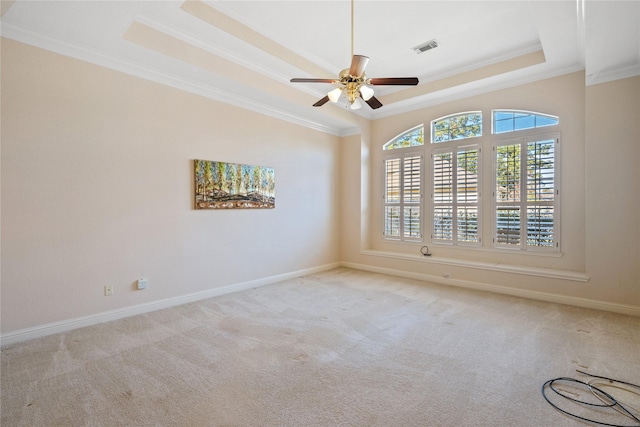 carpeted empty room with a raised ceiling, ceiling fan, and ornamental molding