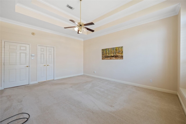 spare room with ceiling fan, light carpet, ornamental molding, and a raised ceiling