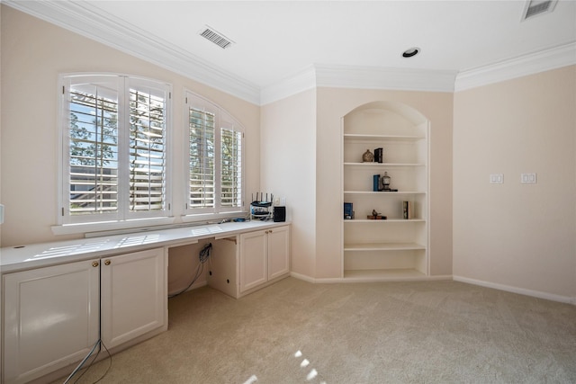 unfurnished office featuring light colored carpet, built in features, ornamental molding, and built in desk