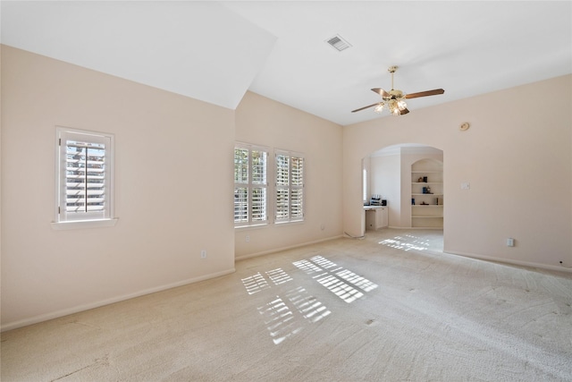 carpeted spare room featuring ceiling fan, plenty of natural light, and built in shelves