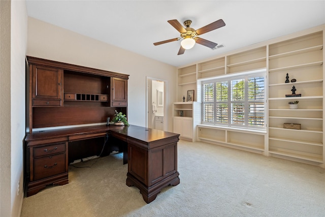 office area with ceiling fan, light carpet, and built in desk