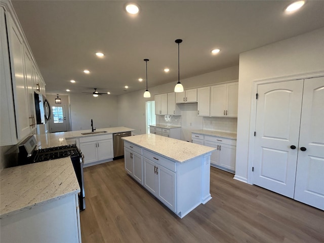 kitchen featuring dark wood finished floors, stainless steel appliances, decorative backsplash, a sink, and a peninsula