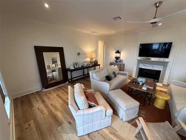 living room featuring ceiling fan, a fireplace, and wood-type flooring