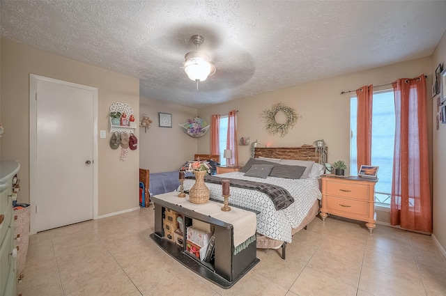 bedroom with ceiling fan, light tile patterned floors, and a textured ceiling