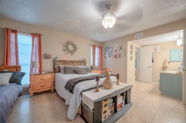 bedroom with ceiling fan, sink, light tile patterned floors, and a textured ceiling