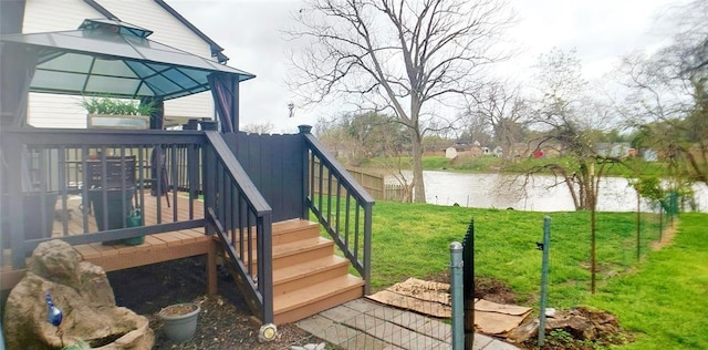 wooden deck with a gazebo, a water view, and a lawn