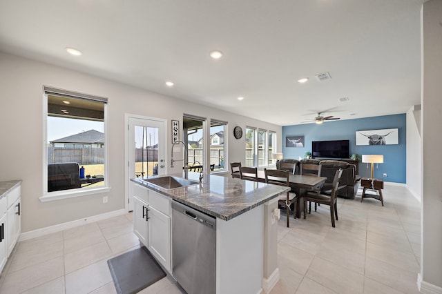 kitchen featuring white cabinets, dark stone counters, sink, dishwasher, and an island with sink