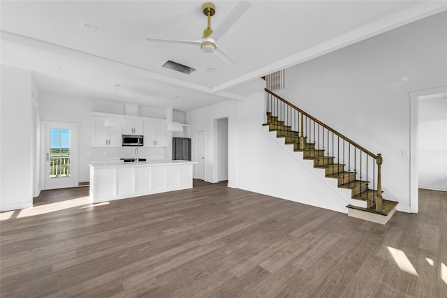 unfurnished living room featuring dark hardwood / wood-style flooring, ceiling fan, and sink