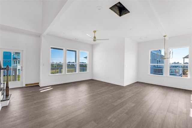 unfurnished living room with dark wood-type flooring and ceiling fan with notable chandelier