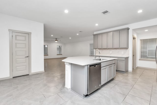 kitchen featuring dishwasher, an island with sink, gray cabinetry, ceiling fan, and sink