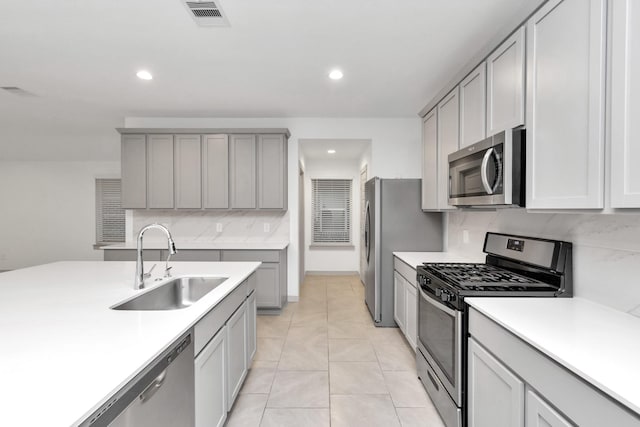 kitchen with light tile patterned floors, appliances with stainless steel finishes, gray cabinets, and sink