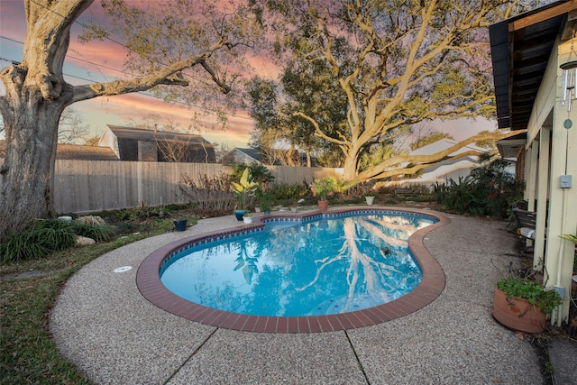 pool at dusk with a fenced backyard and a fenced in pool