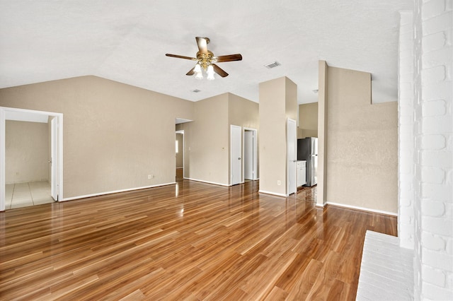 unfurnished living room with ceiling fan, wood-type flooring, and vaulted ceiling