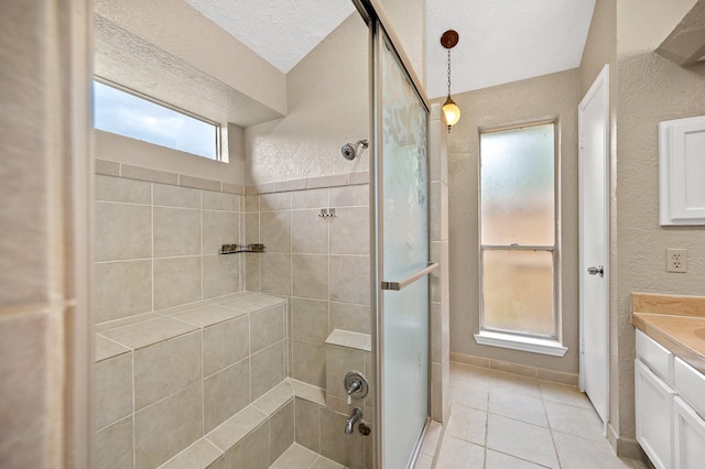 bathroom with tile patterned flooring, vanity, a tile shower, and a textured ceiling