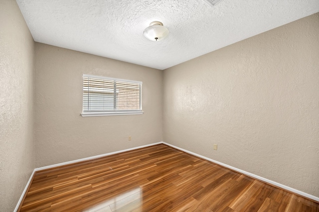 spare room featuring wood-type flooring and a textured ceiling