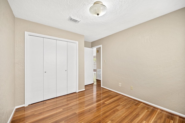 unfurnished bedroom with a closet, wood-type flooring, and a textured ceiling