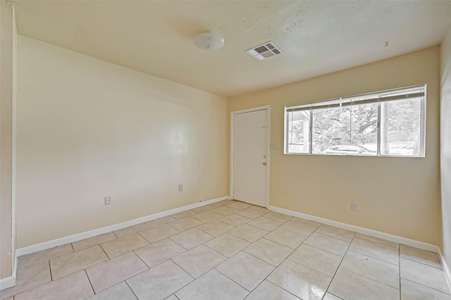 empty room featuring a textured ceiling and light tile patterned floors