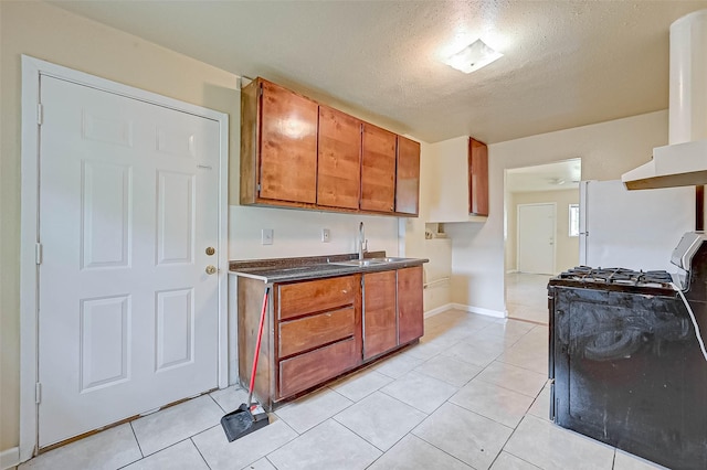 kitchen with range with gas cooktop, light tile patterned floors, a textured ceiling, exhaust hood, and sink