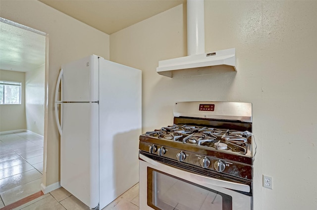 kitchen with white fridge, light tile patterned flooring, and gas stove