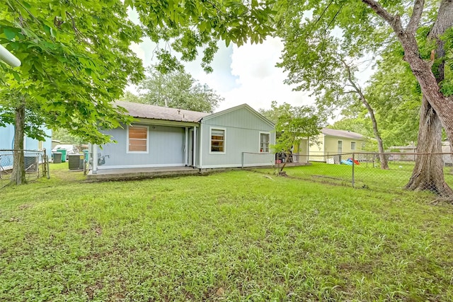 rear view of house featuring central air condition unit and a yard