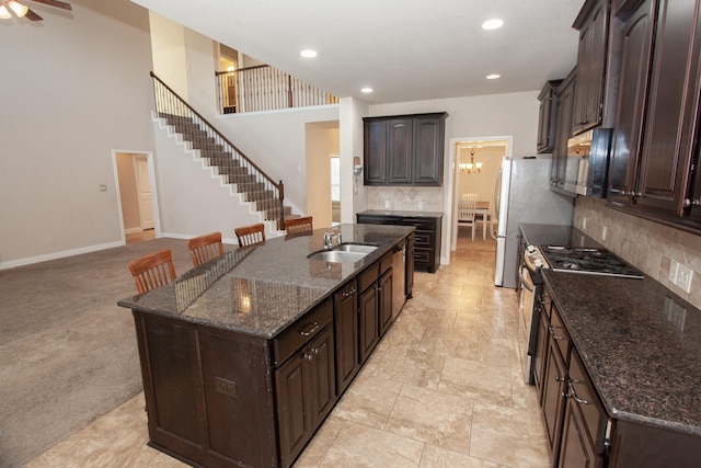 kitchen with appliances with stainless steel finishes, backsplash, dark brown cabinets, and sink