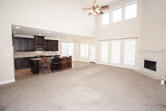 living room with carpet floors, a wealth of natural light, ceiling fan, and a towering ceiling