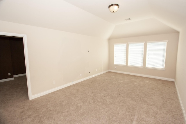 carpeted spare room with lofted ceiling