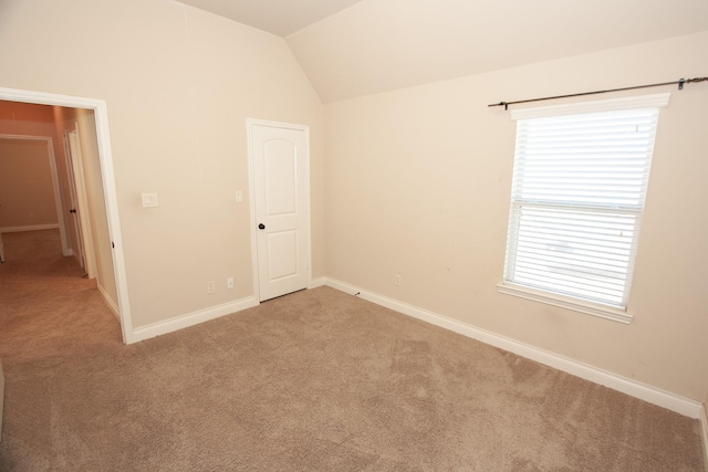 carpeted empty room featuring lofted ceiling