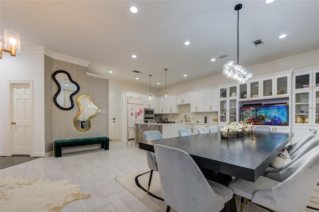 dining room featuring a chandelier, light tile patterned floors, and ornamental molding