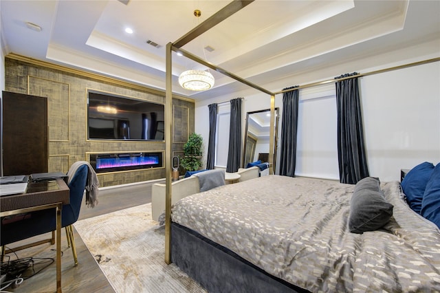 bedroom with a raised ceiling, wood-type flooring, and ornamental molding