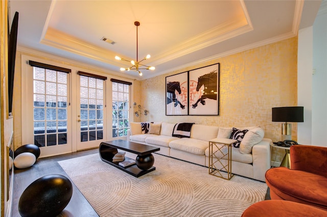 living room with french doors, crown molding, hardwood / wood-style flooring, a tray ceiling, and a notable chandelier