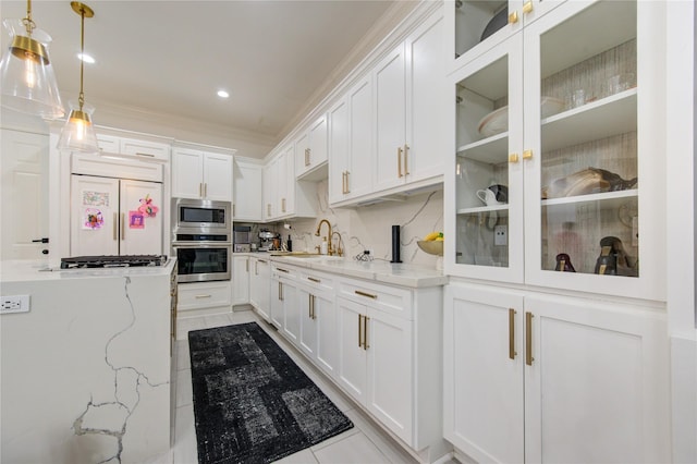 kitchen with built in appliances, white cabinetry, light stone counters, and sink