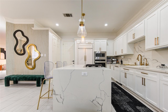 kitchen featuring sink, built in appliances, decorative light fixtures, a kitchen island, and white cabinetry