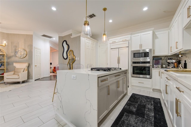 kitchen with light stone countertops, a center island, built in appliances, decorative light fixtures, and white cabinets