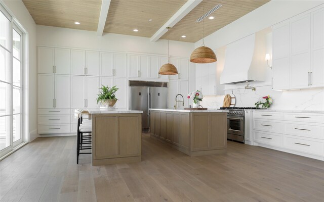 kitchen featuring white cabinets, wooden ceiling, a large island with sink, high end appliances, and custom exhaust hood