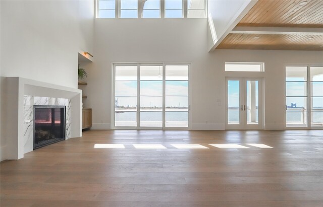 unfurnished living room with a high ceiling, a premium fireplace, french doors, and wood ceiling