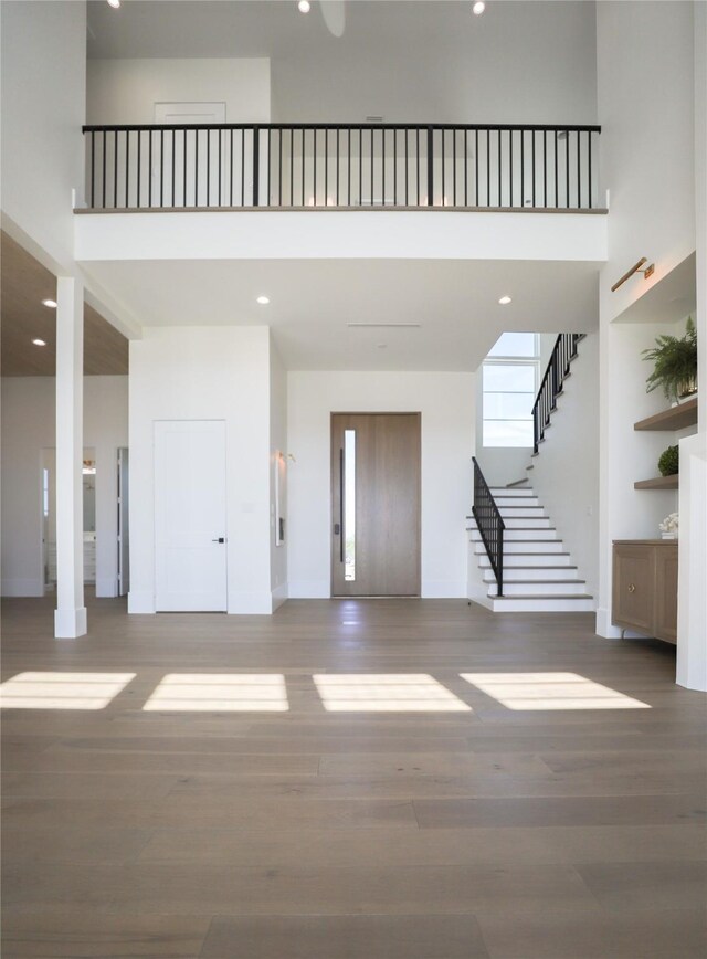 entryway featuring elevator, a towering ceiling, and wood-type flooring