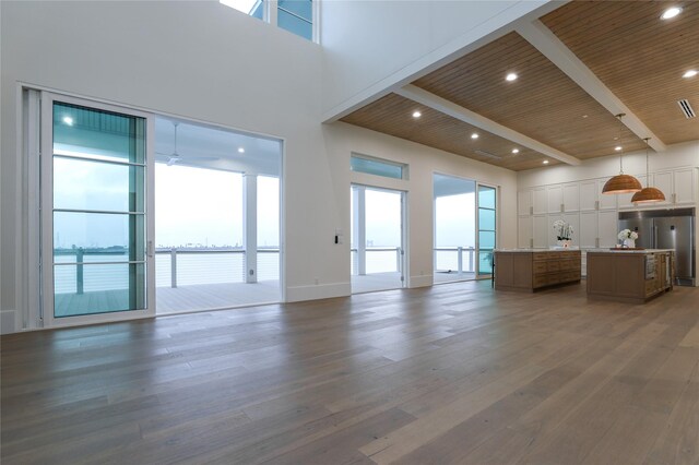 unfurnished living room with wooden ceiling, beamed ceiling, ceiling fan, dark wood-type flooring, and a high ceiling