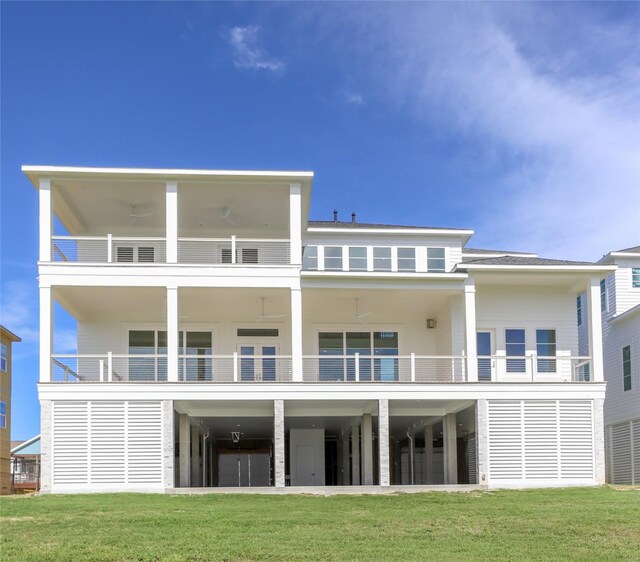 rear view of property with a balcony, a carport, and a lawn