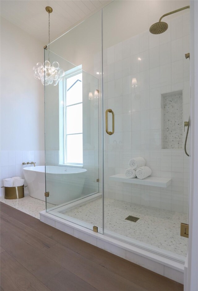 bathroom with shower with separate bathtub and a chandelier