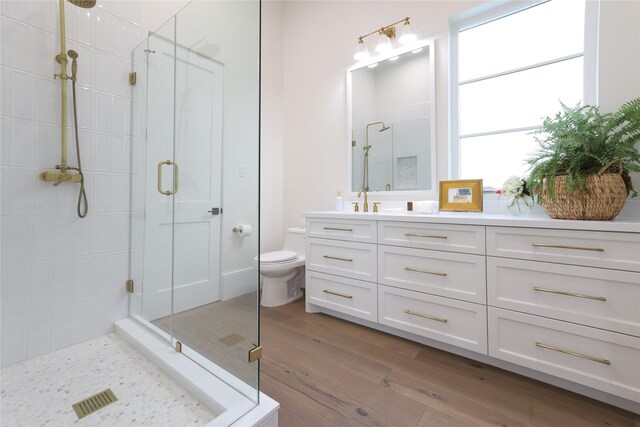 bathroom featuring toilet, hardwood / wood-style flooring, plenty of natural light, a shower with shower door, and vanity