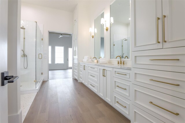 bathroom with a shower with door, hardwood / wood-style floors, and vanity