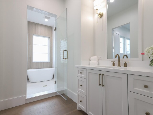 bathroom featuring hardwood / wood-style flooring, independent shower and bath, and vanity