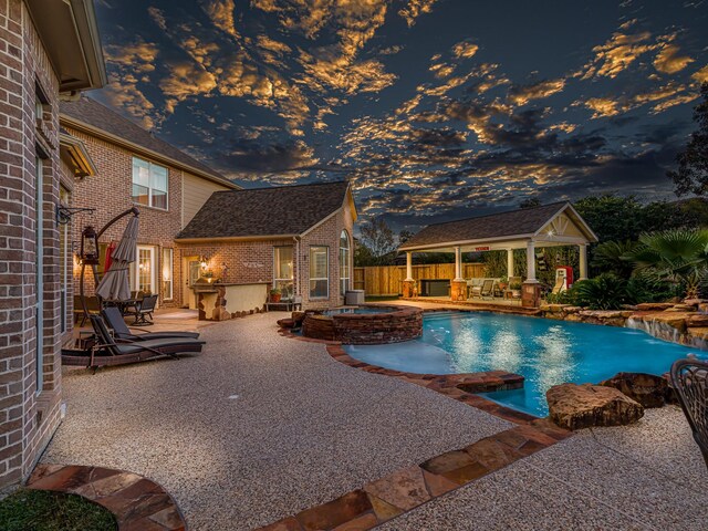 pool at dusk featuring a gazebo, outdoor lounge area, an in ground hot tub, and a patio