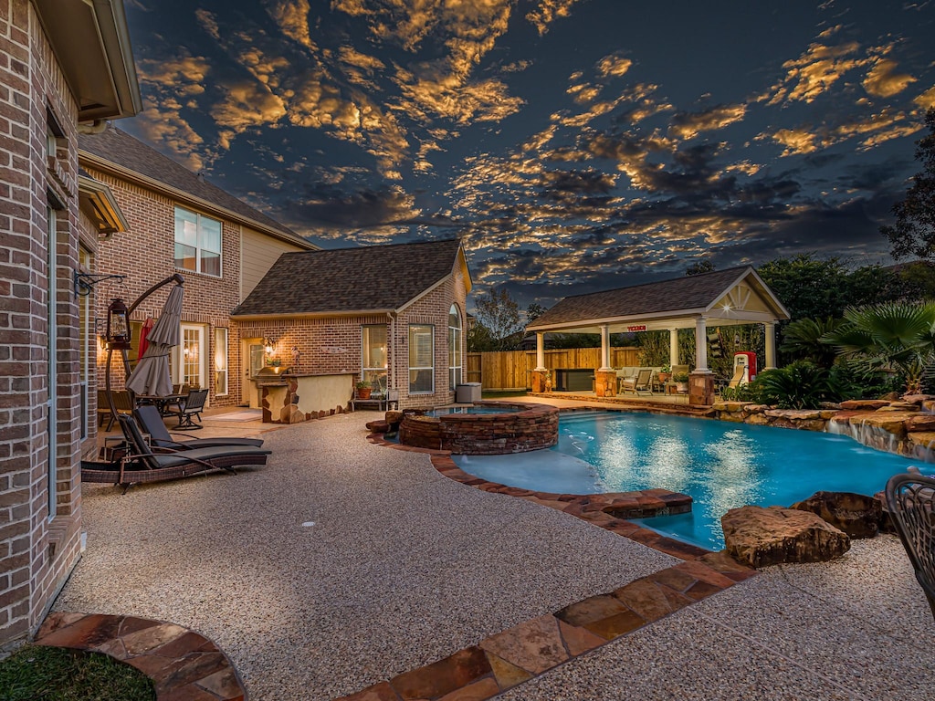 pool at dusk featuring an in ground hot tub, a patio area, a gazebo, and outdoor lounge area