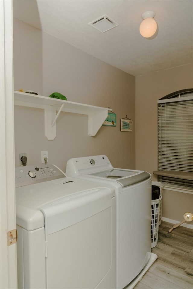 clothes washing area featuring washer and clothes dryer and light wood-type flooring