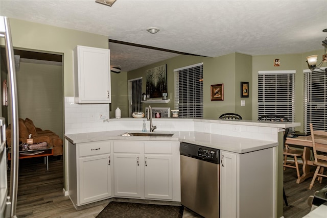 kitchen with sink, white cabinetry, kitchen peninsula, stainless steel dishwasher, and wood-type flooring