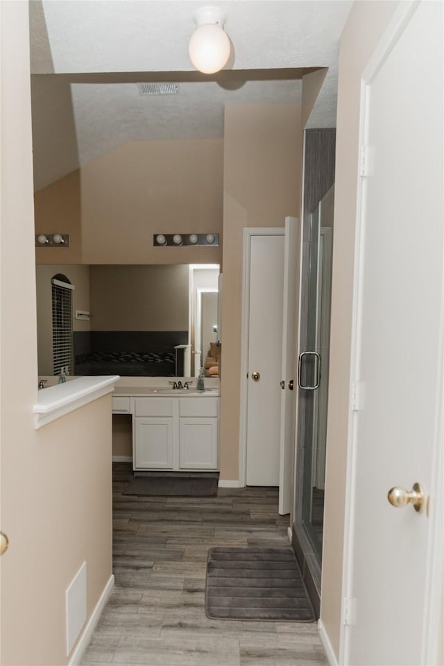 bathroom with hardwood / wood-style floors, a shower with door, and vanity