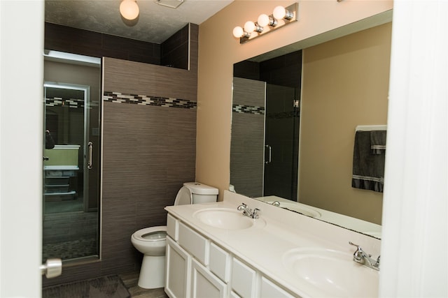 bathroom featuring toilet, a shower with door, a textured ceiling, and vanity