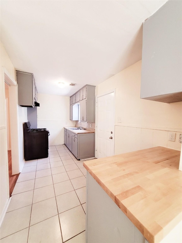 kitchen with light tile patterned flooring, gray cabinets, range with gas cooktop, and sink